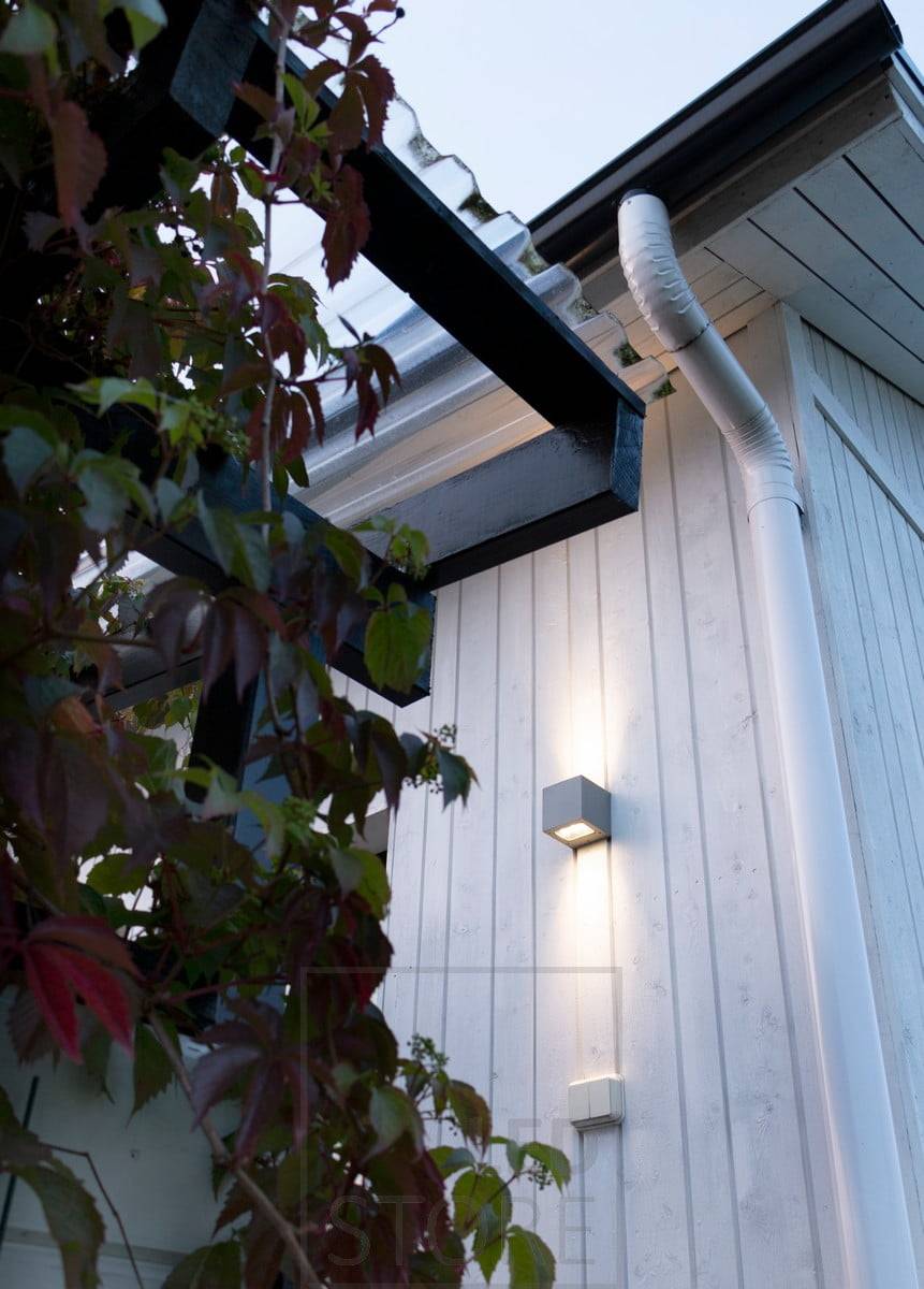 CUBIC OUT 2 en la pared de una casa, iluminando en dos direcciones con una luz cálida y atmosférica.